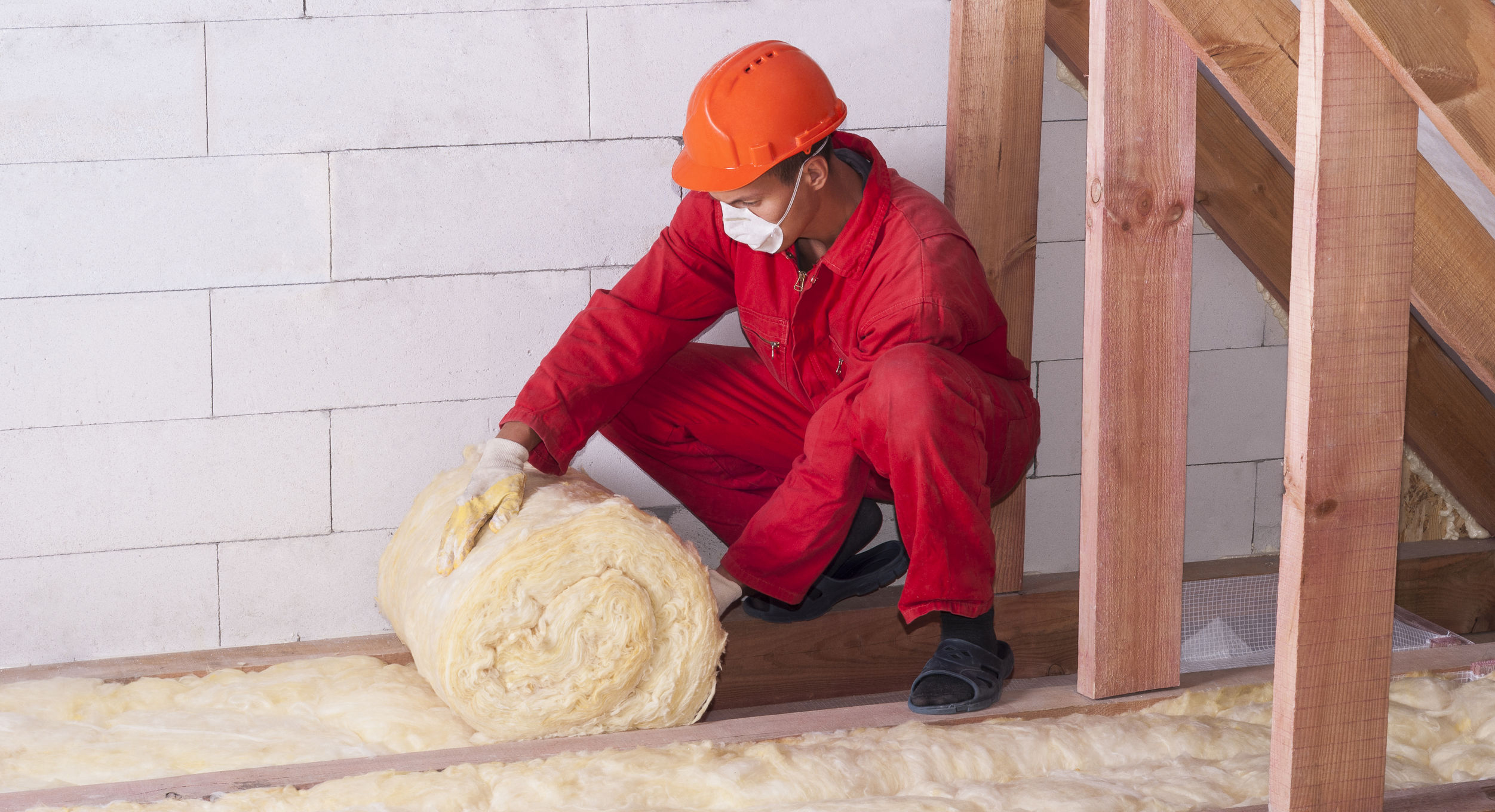 Worker installing insulation in an attic