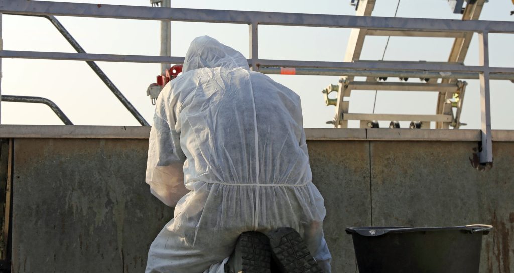 Professional in protective gear performing asbestos abatement