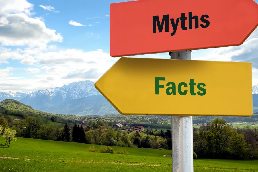 Street signs saying myths and facts in front of road and landscape