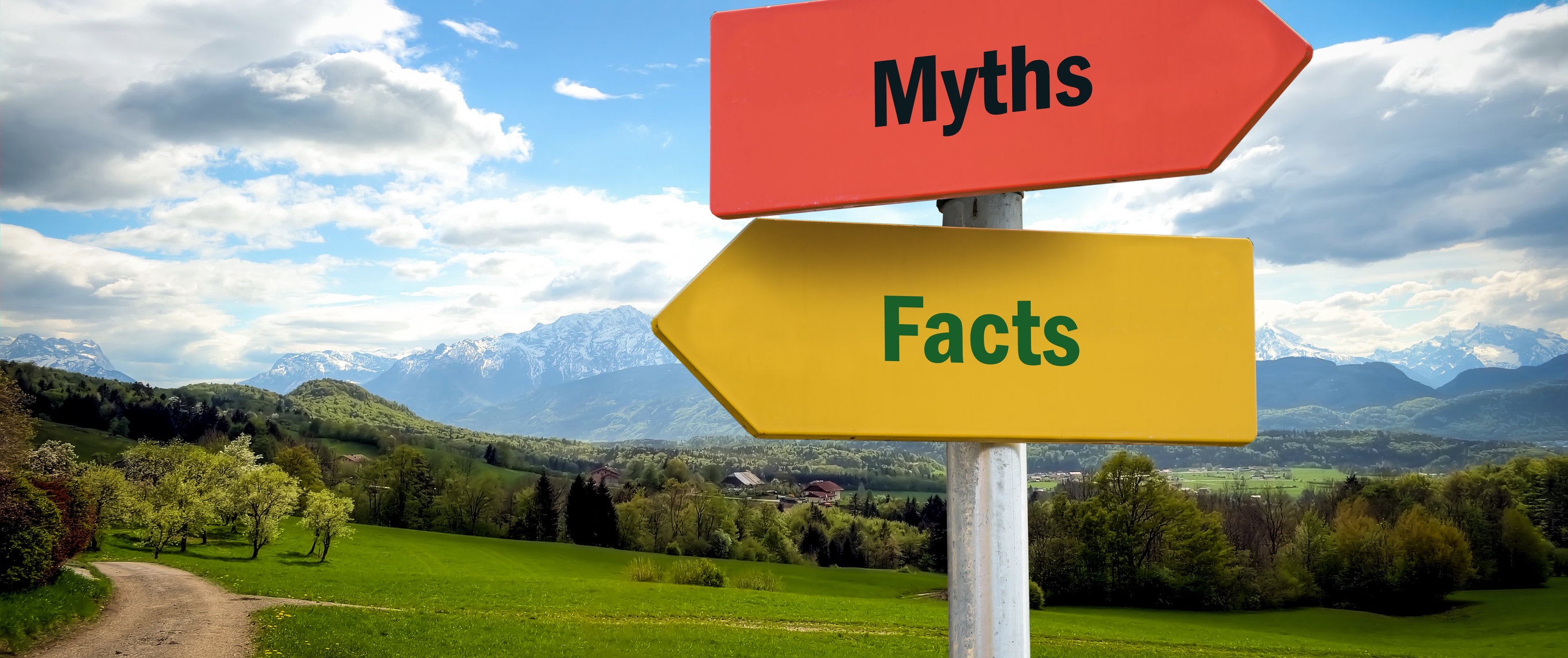 Street signs saying myths and facts in front of road and landscape