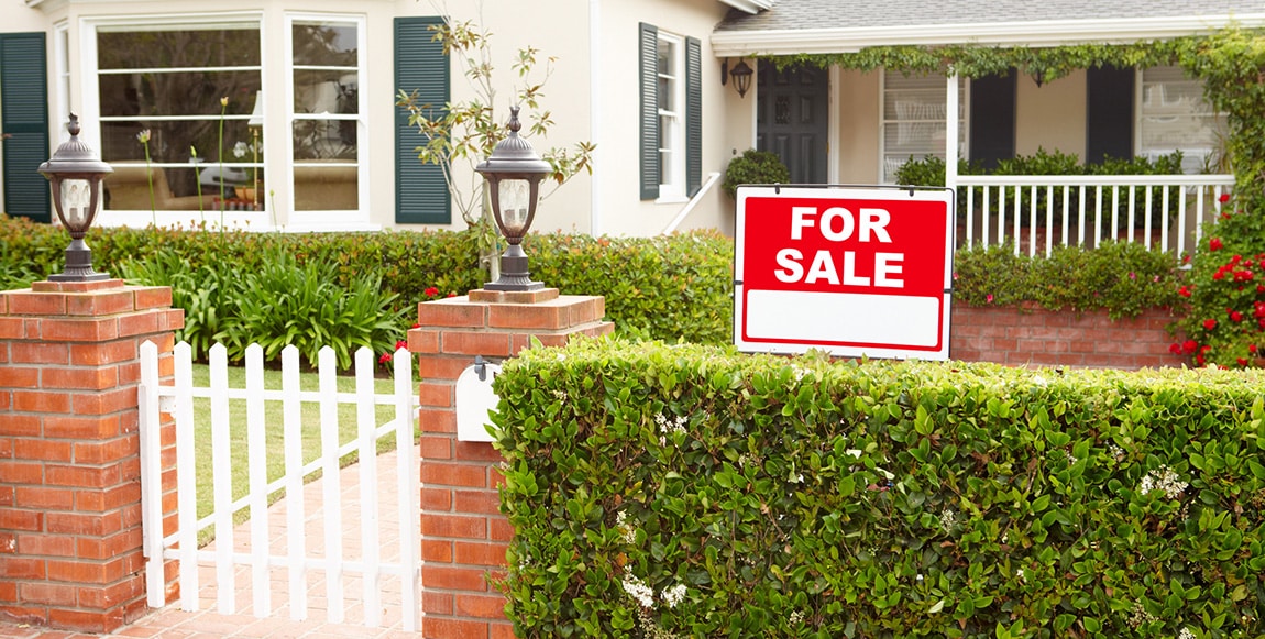 Front of a house with a for sale sign in the yard